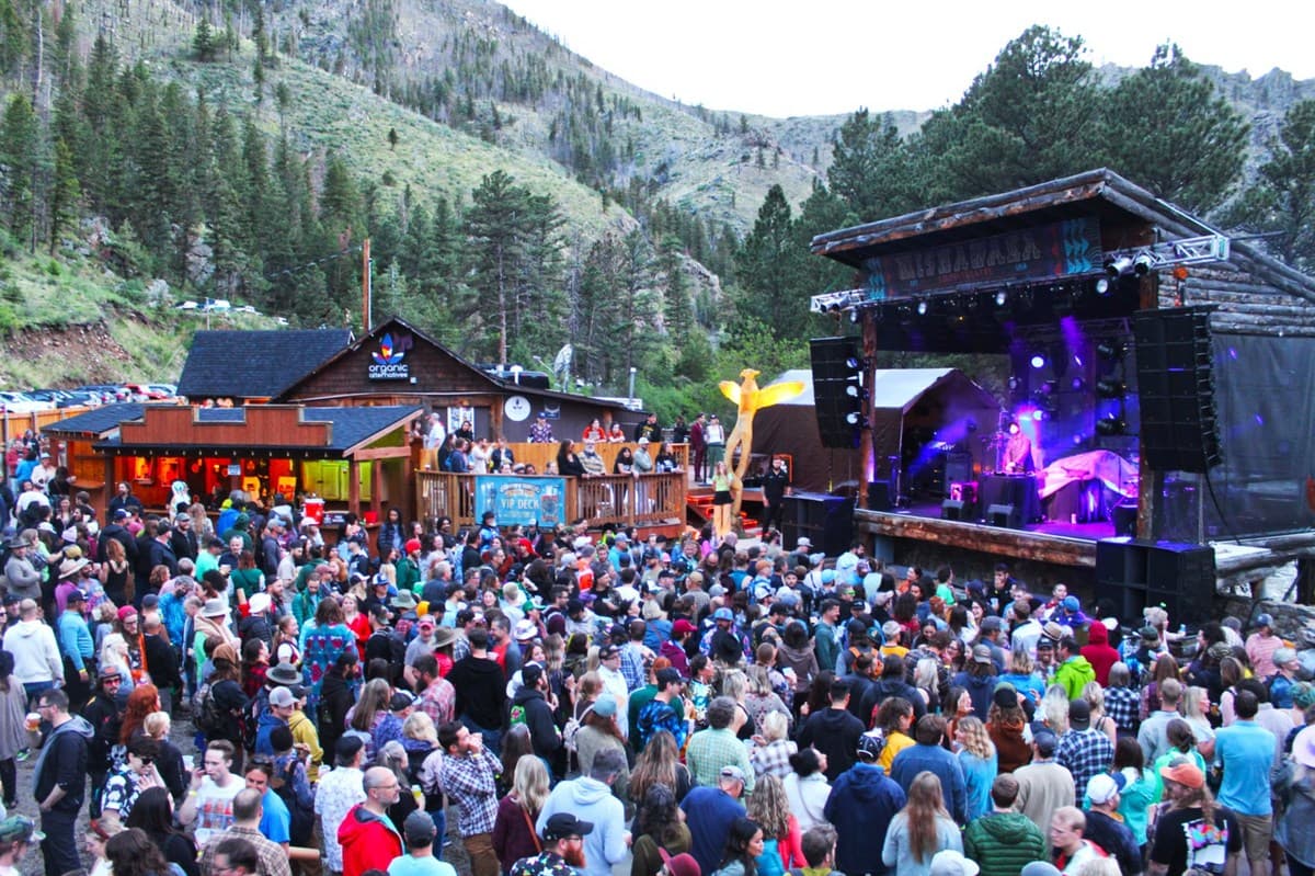 Mountain venue festival stage with purple lighting and a large crowd