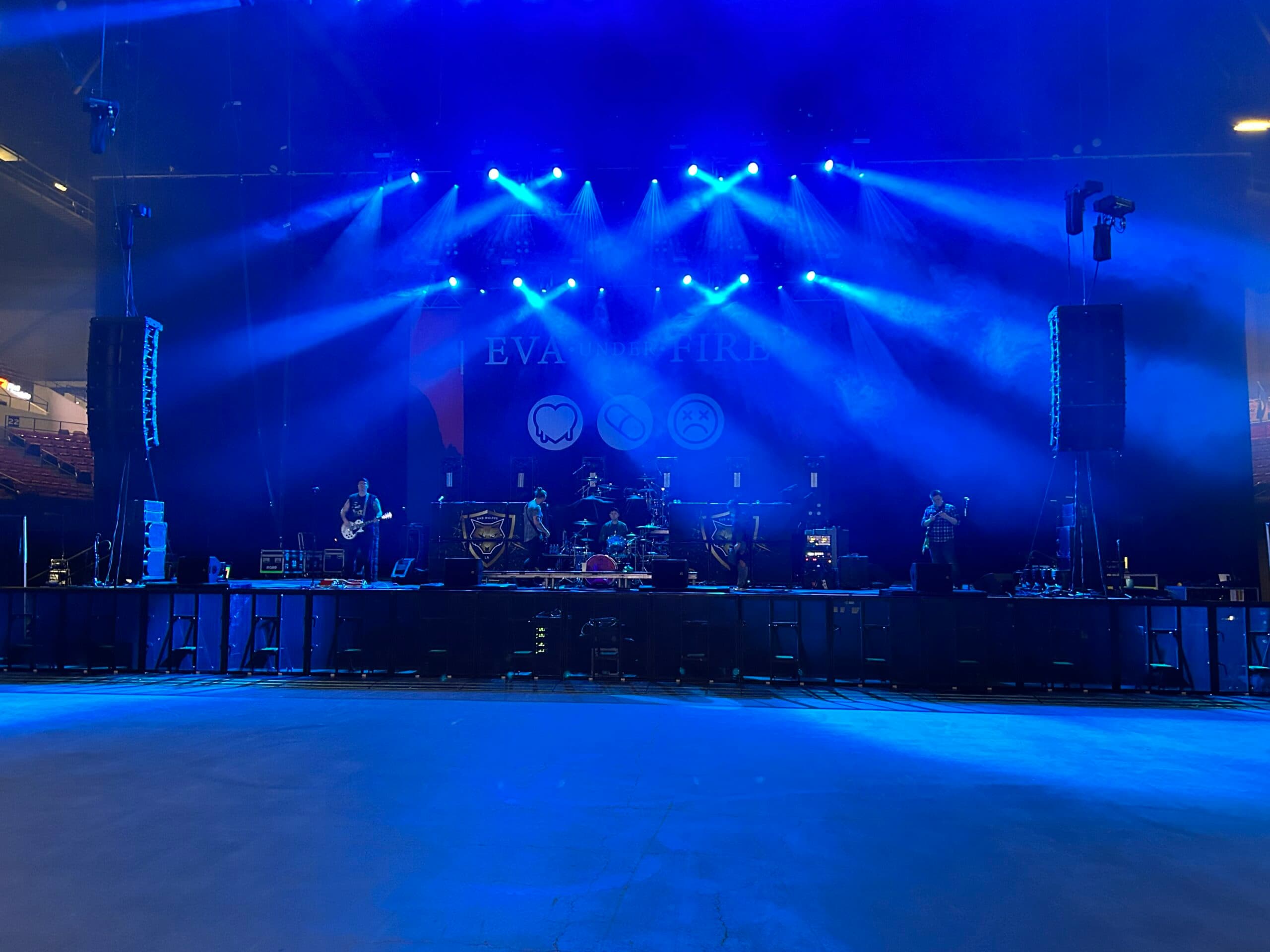 Concert stage lit in vivid blue with line-array PA hung stage left and right